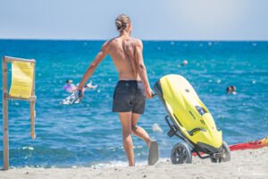 Homme marchant sur une plage corse avec un kayak jaune, capturant l'esprit des vacances et des activités nautiques