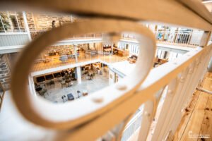 Photographie d'une bibliothèque contemporaine avec étagères en bois, inondée de lumière naturelle.