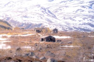Scène sereine des cabanes montagnardes sous la neige fondante avec reflets printaniers