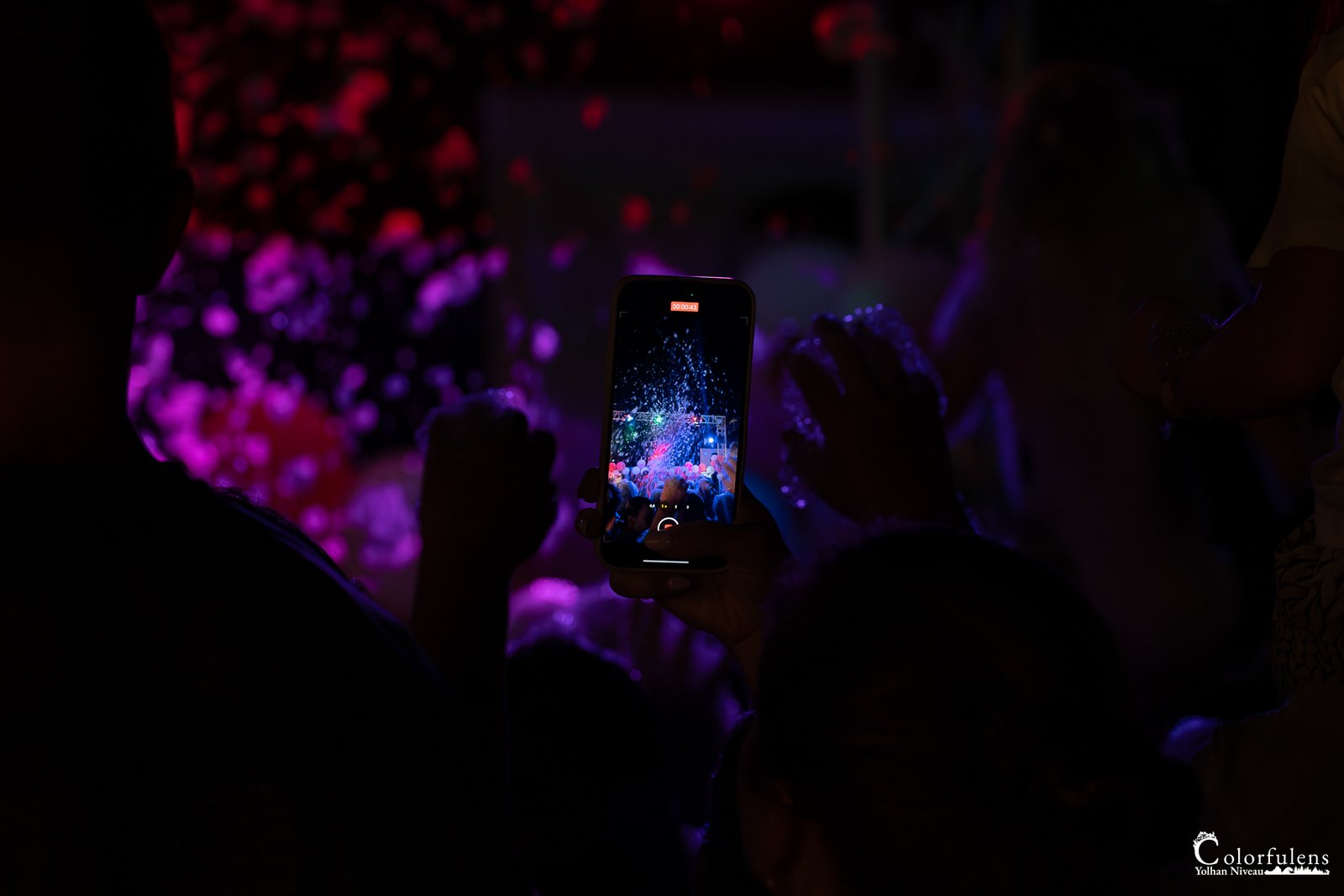 Scène de concert vibrant au crépuscule, illuminateurs et smartphones immortalisant l'ambiance.