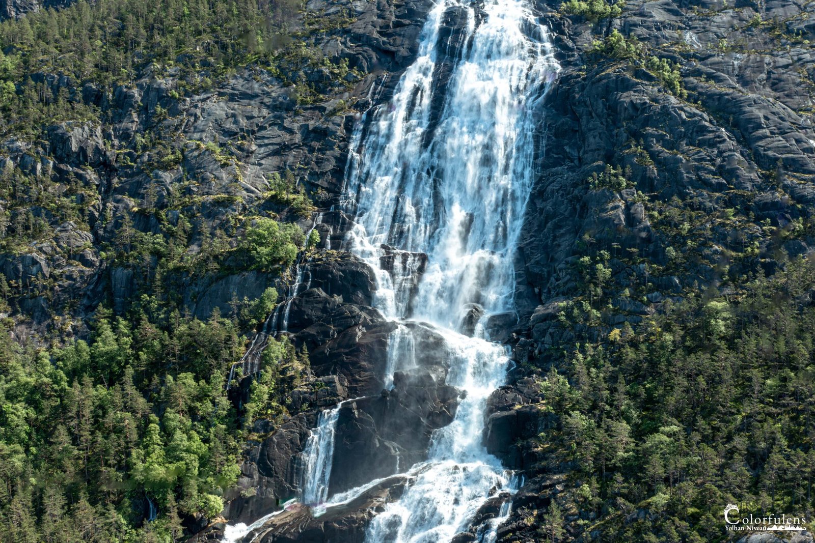 Chute d'eau spectaculaire dévalant les montagnes et entourée d'une végétation luxuriante, reflétant la majesté de la nature.