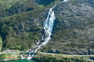 Photo de cascade spectaculaire dans une montagne verdoyante avec un pont en arc, montrant la tranquillité et la puissance de la nature.