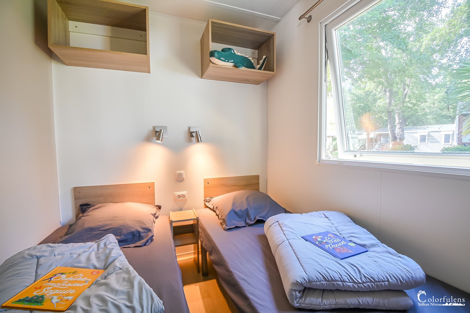 Chambre moderne minimaliste avec deux lits simples, baignée de lumière naturelle, idéale pour un repos serein.