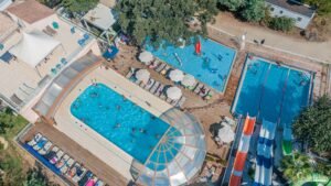 Vue aérienne du camping Merendella en Corse, affichant un complexe aquatique animé avec piscines et toboggans, idéal pour des vacances en famille.