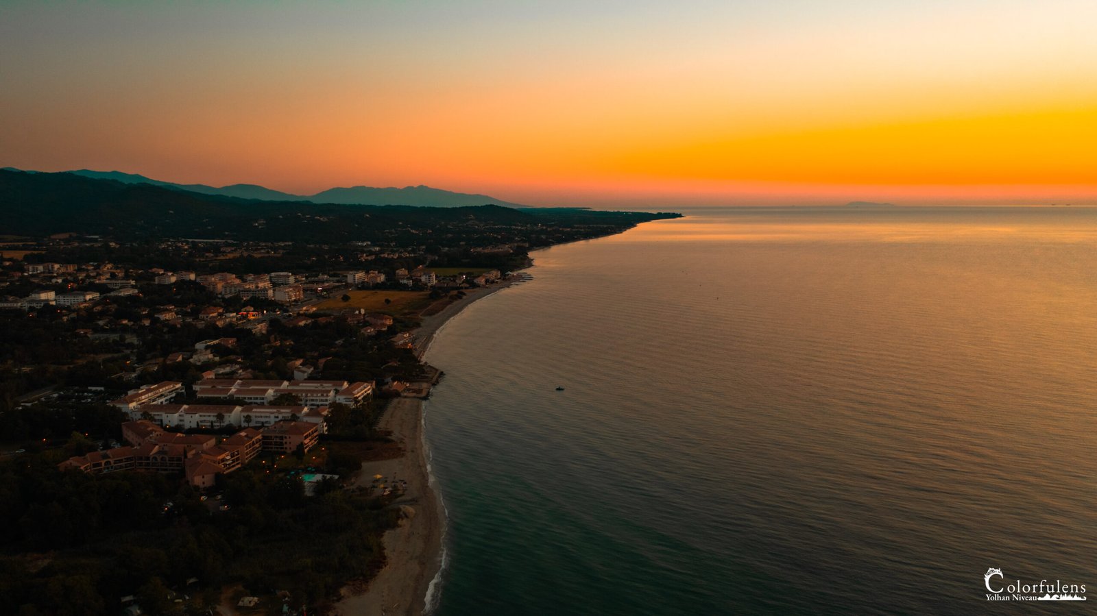Coucher de soleil captivant en Corse avec des nuances vibrantes sur la mer et les montagnes, illustrant calme et beauté naturelle.