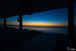 Coucher de soleil sur une plage calme avec des chaises longues vides, soulignant une ambiance paisible et harmonieuse.