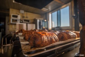 Des croissants dorés fraîchement sortis du four illuminés par une douce lumière matinale dans une boulangerie française