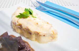 Image de fromage fondant garni de fines herbes sur une tranche de pain, capturant l'essence de la cuisine française raffinée.