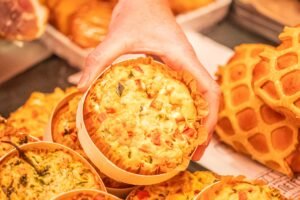 L'image de quiches artisanales dorées, présentées dans un marché, souligne leur artisanat et gourmandise, parfaites pour savourer un repas convivial.