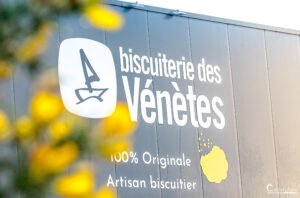 Enseigne de la Biscuiterie des Vénètes sur fond de ciel nuageux, mettant en avant l'authenticité et le savoir-faire artisanal.