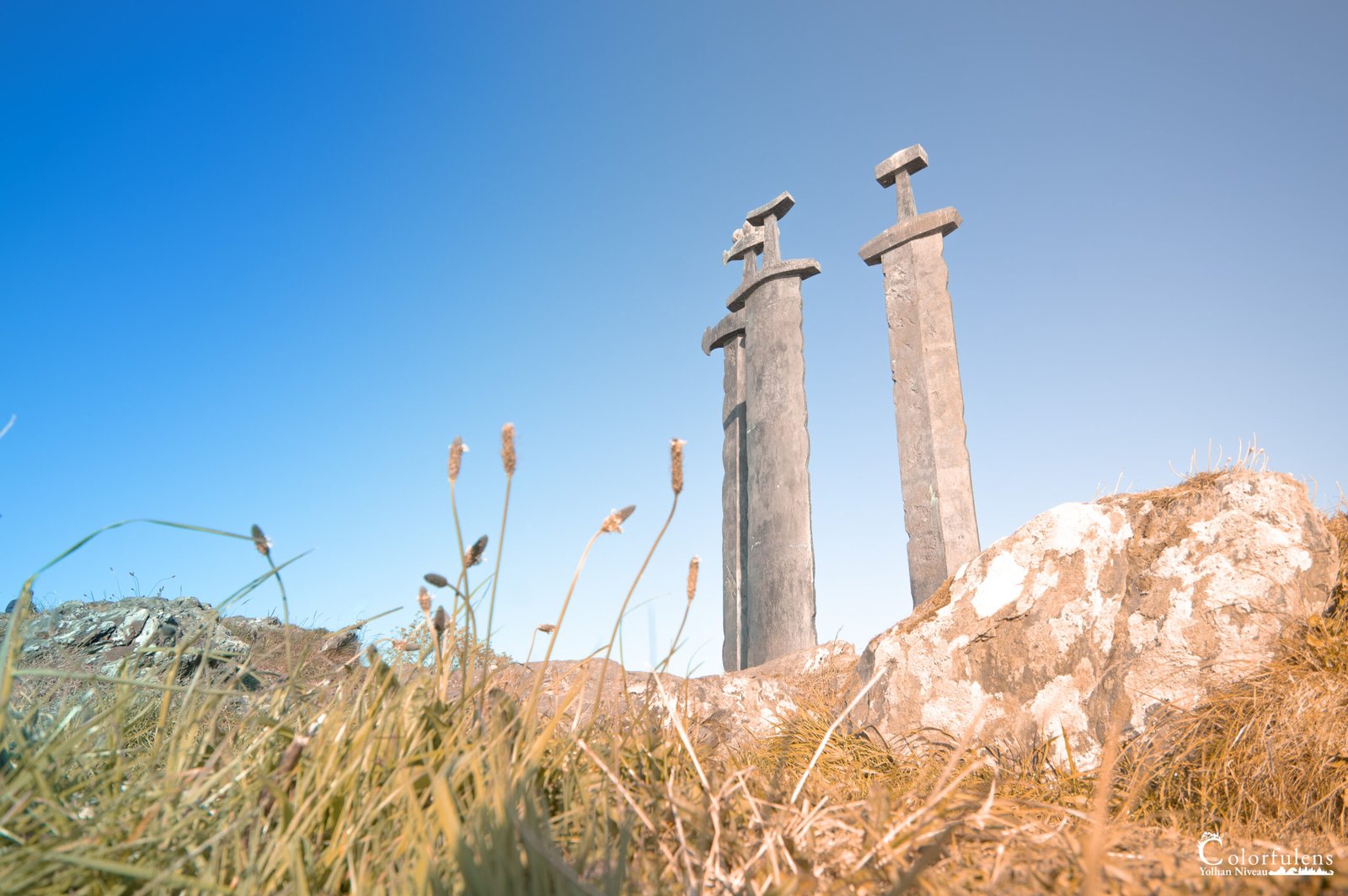 Sculptures monumentales d'épées en pierre s'élevant vers un ciel dégagé, symboles de bravoure et d'histoire.