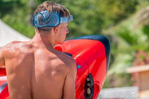 Jeune homme avec masque et tuba prêt à plonger dans l'Aqua Parc Merendella, tenant une bouée rouge.