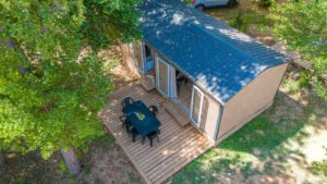 Chalet en bois avec terrasse au milieu des arbres, parfait pour une retraite en pleine nature et une évasion relaxante.