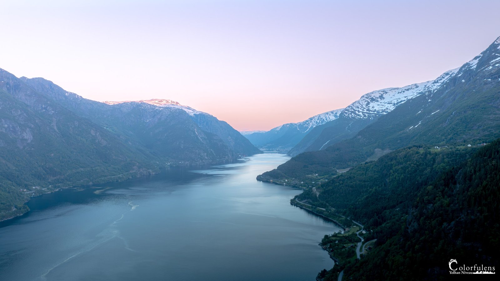 Photographie captivante du Hardangerfjord en Norvège au crépuscule avec reflets parfaits sur l'eau et montagnes majestueuses.
