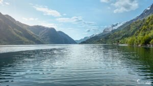 Vue spectaculaire du Hardangerfjord en Norvège avec reflets montagneux sur des eaux tranquilles.