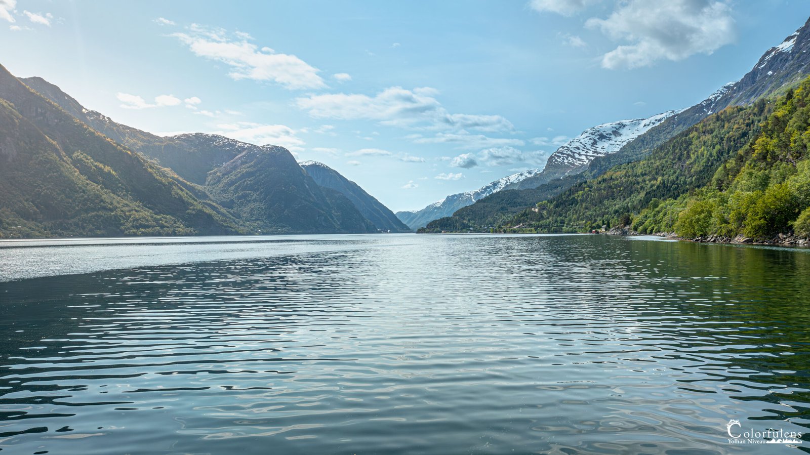 Vue spectaculaire du Hardangerfjord en Norvège avec reflets montagneux sur des eaux tranquilles.