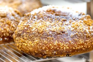 Donut doré avec sucre et éclats de noisette attirant sur fond de pâtisserie