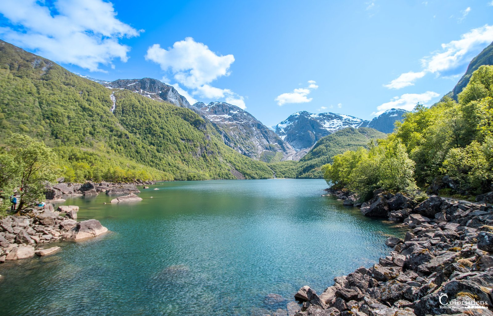 Un oasis de paix norvégien avec montagnes enneigées, lac miroir et verdure luxuriante.