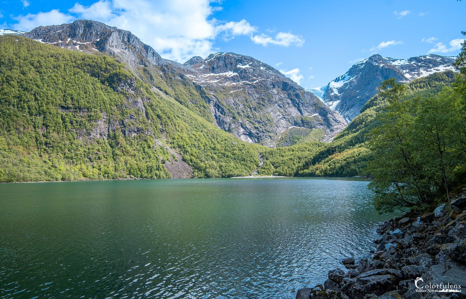Image du lac Bondhusvatnet en Norvège avec reflets chatoyants, montagnes et paysages verdoyants