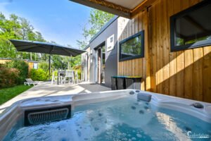 Logement de vacances moderne offrant un jacuzzi extérieur au cœur d'un jardin verdoyant, fusionnant luxe et nature pour une évasion complète.