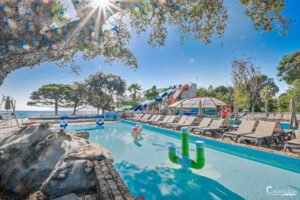 Un parc aquatique coloré et animé au camping Merendella en Corse, invitant à la détente sous un ciel radieux.