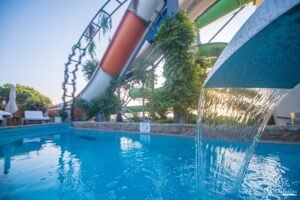 Parc aquatique avec piscine et toboggans sous un ciel ensoleillé, offrant détente et aventure pour toute la famille.