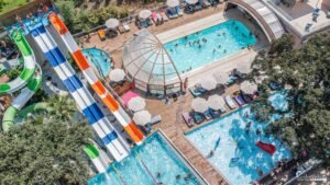 Vue aérienne d'un parc aquatique animé avec toboggans colorés et piscines, incarnant la joie estivale.