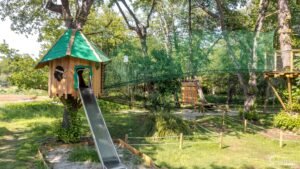 Ce parc aventure pour enfants au cœur de la nature propose des jeux sécurisés avec une cabane en bois et un toboggan.