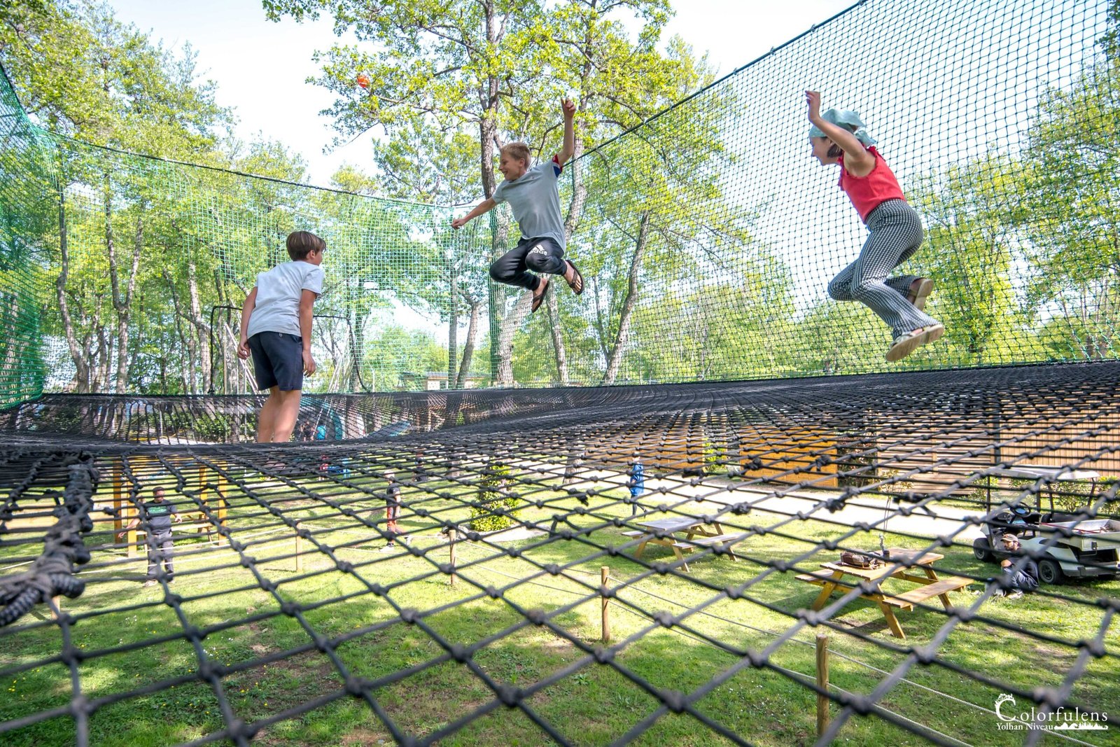 Des enfants s'amusent dans un parc d'aventure en plein air, profitant de jeux actifs et d'un apprentissage par l'expérience dans un cadre naturel sécurisé.