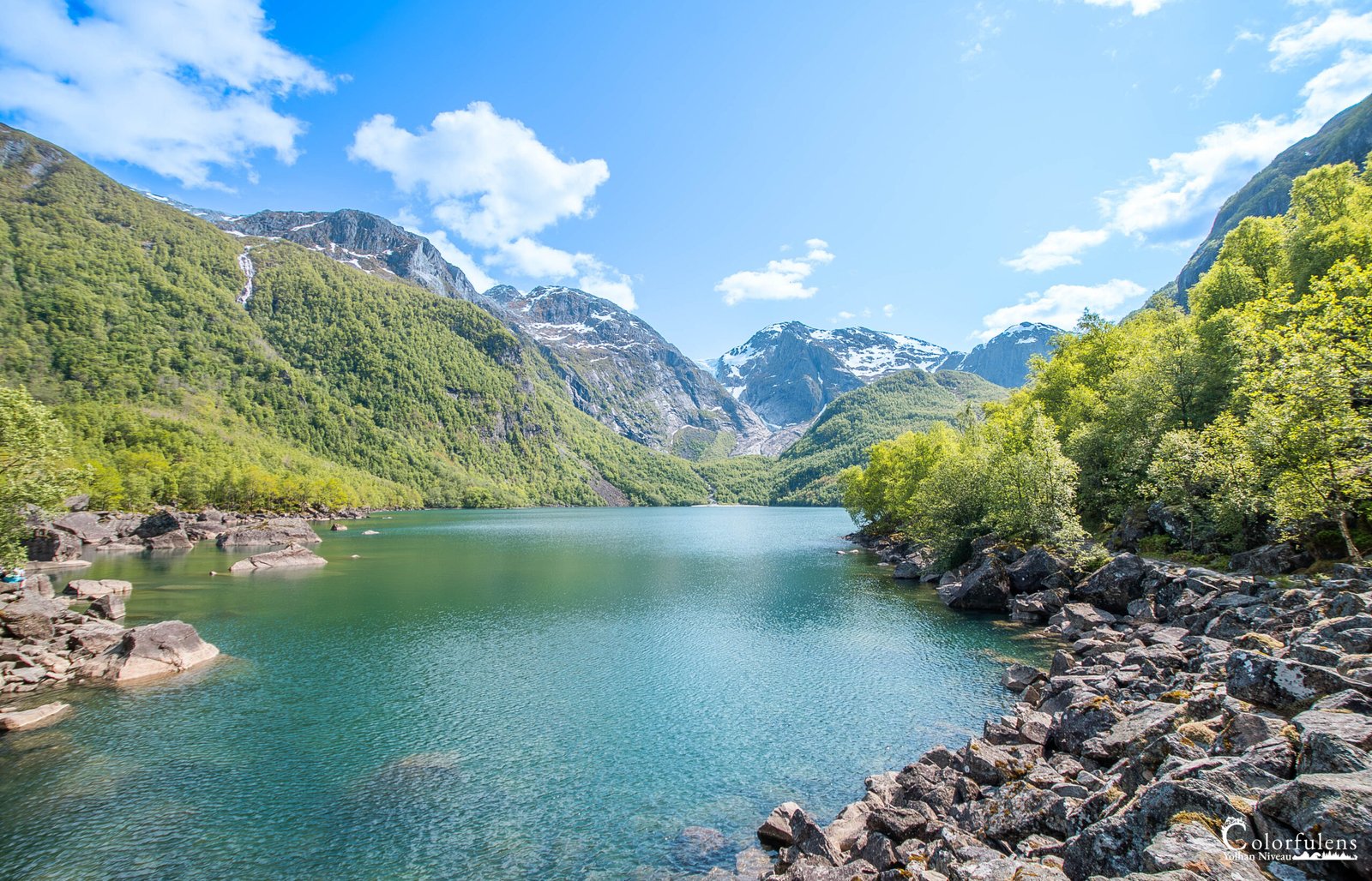 Sérénité captivante d'un lac alpin bleu azur entouré de pics enneigés et de végétation luxuriante