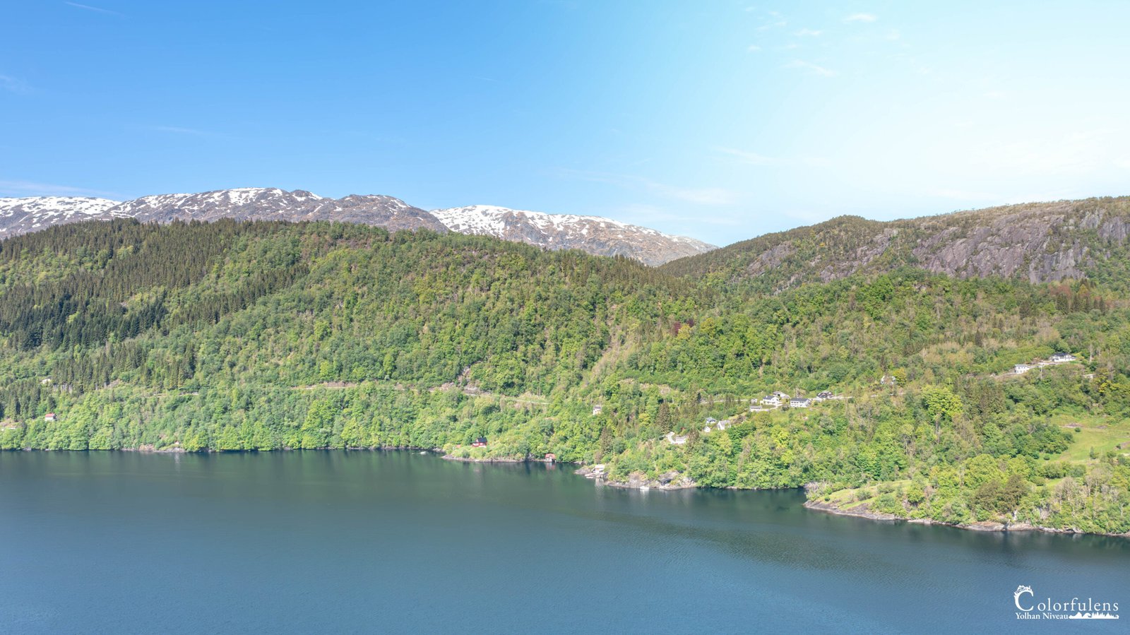 Une vue époustouflante des fjords norvégiens, où des montagnes enneigées surplombent des eaux claires et tranquilles.