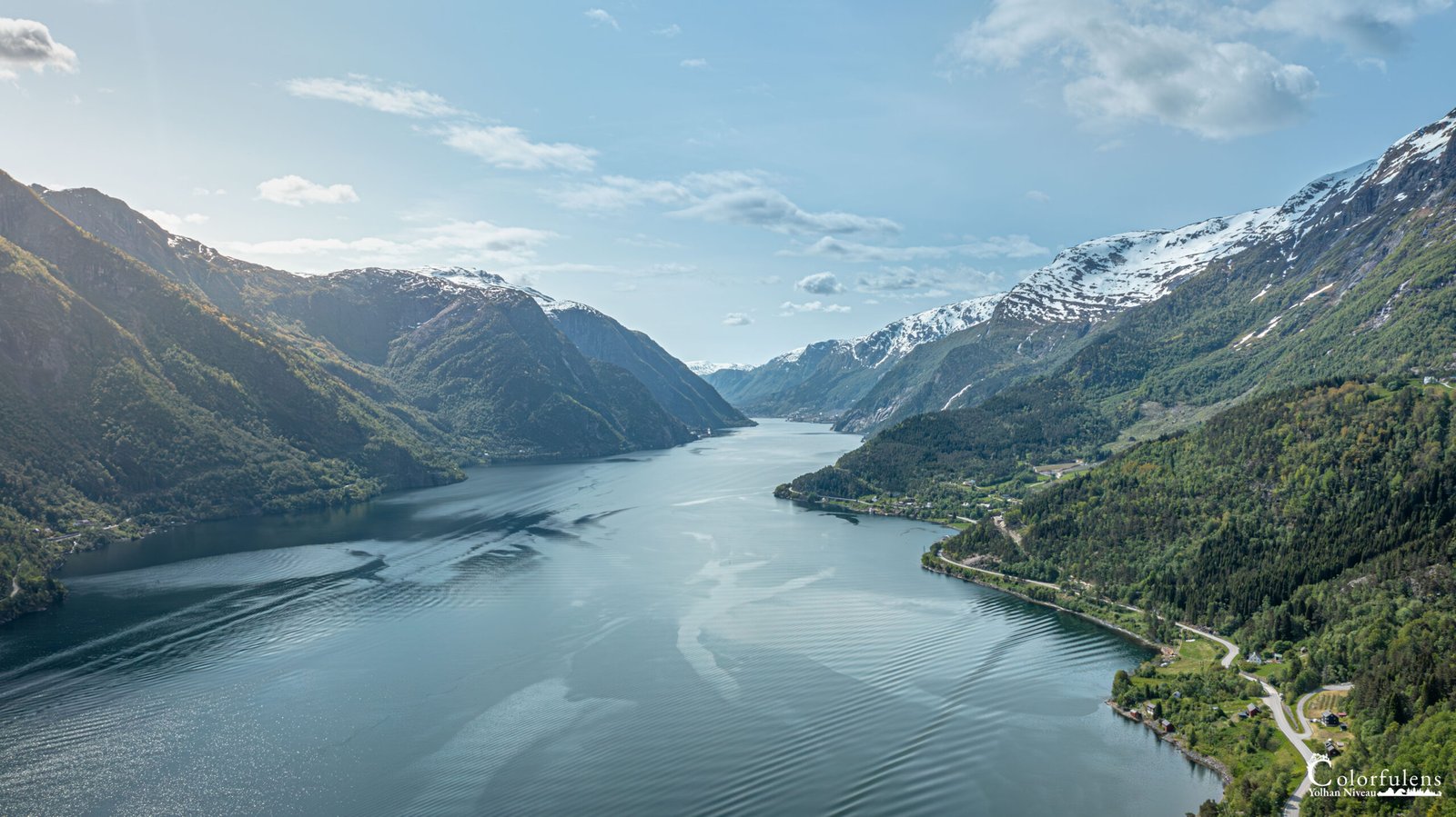 Panorama spectaculaire du fjord norvégien Hardanger avec montagnes enneigées et reflets dans l'eau