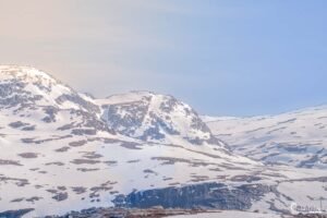 Montagne enneigée sous un ciel sans nuages, offrant un spectacle de tranquillité avec une neige immaculée éblouissante sous la lumière naturelle.