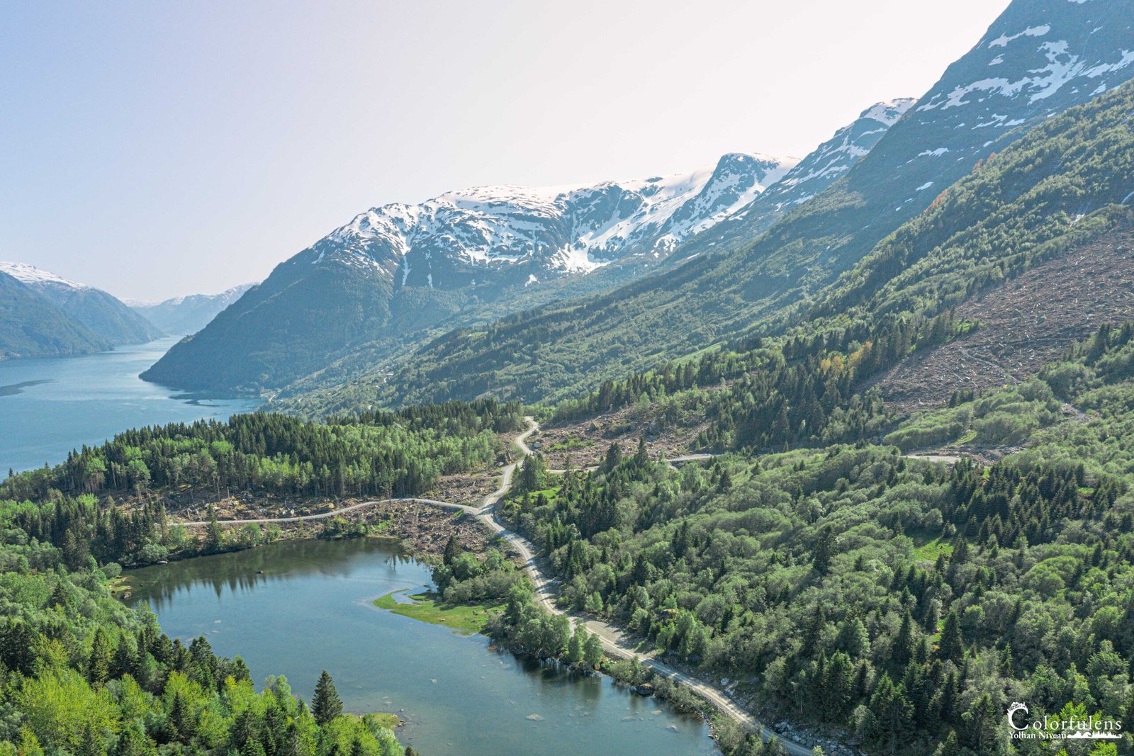 Image d'un havre de paix naturel montrant un lac entouré de montagnes enneigées et de verdure, évoquant pureté et tranquillité.