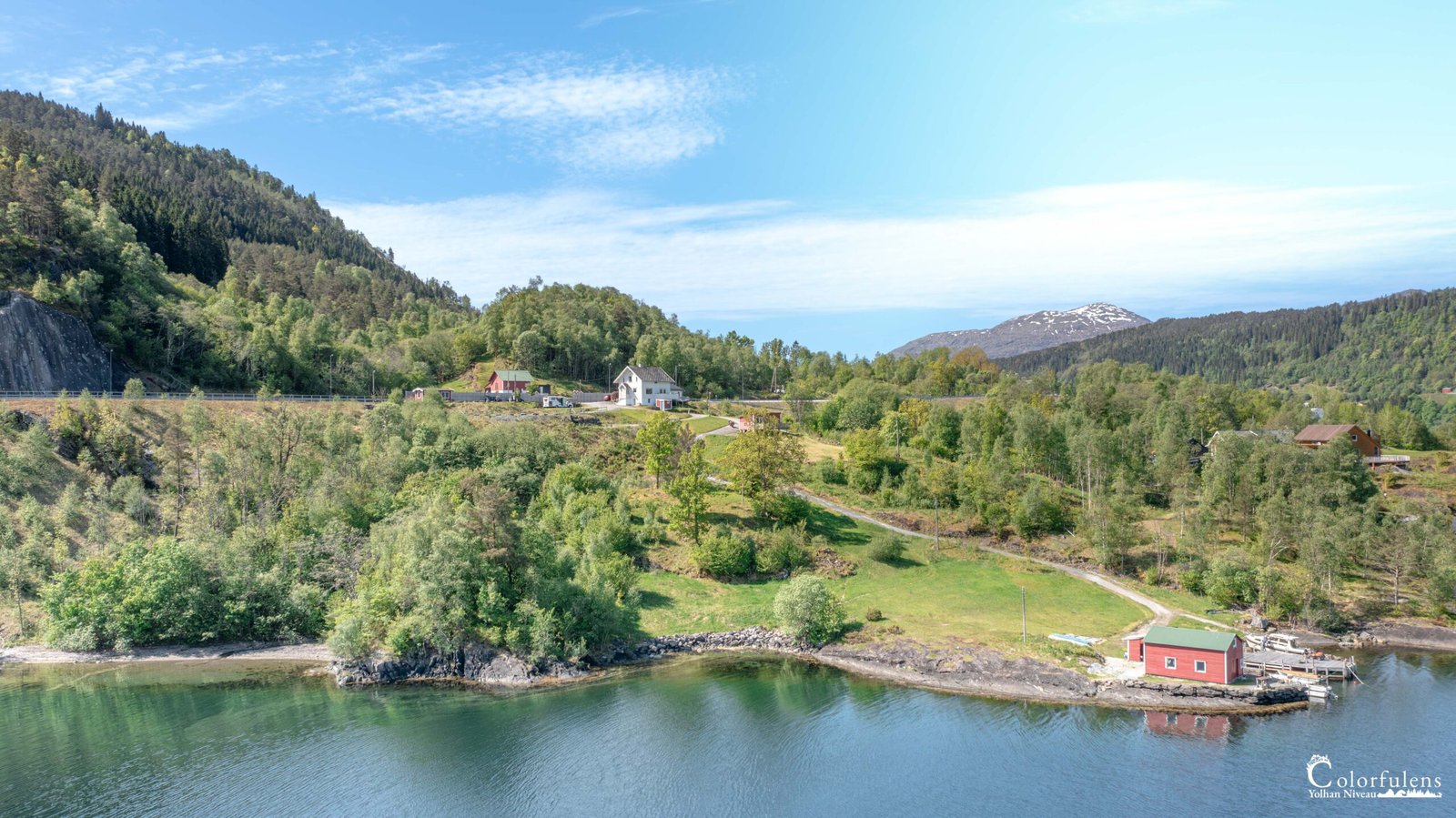 Maisons scandinaves pittoresques au bord d'un fjord glacé, entourées de montagnes et de verdure en Norvège, évoquant la tranquillité et la beauté sauvage.
