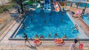 Activités aquatiques estivales avec enfants au parc aquatique du camping, glissades sur toboggans colorés sous un soleil éclatant