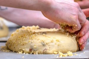 Un artisan passionné façonne une pâte à biscuit saupoudrée de miettes, capturant l'essence de la biscuiterie artisanale et traditionnelle.