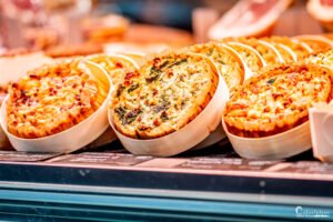 Quiches artisanales exposées dans un marché local français, mettant en valeur les spécialités culinaires de terroir avec des ingrédients frais et savoureux.