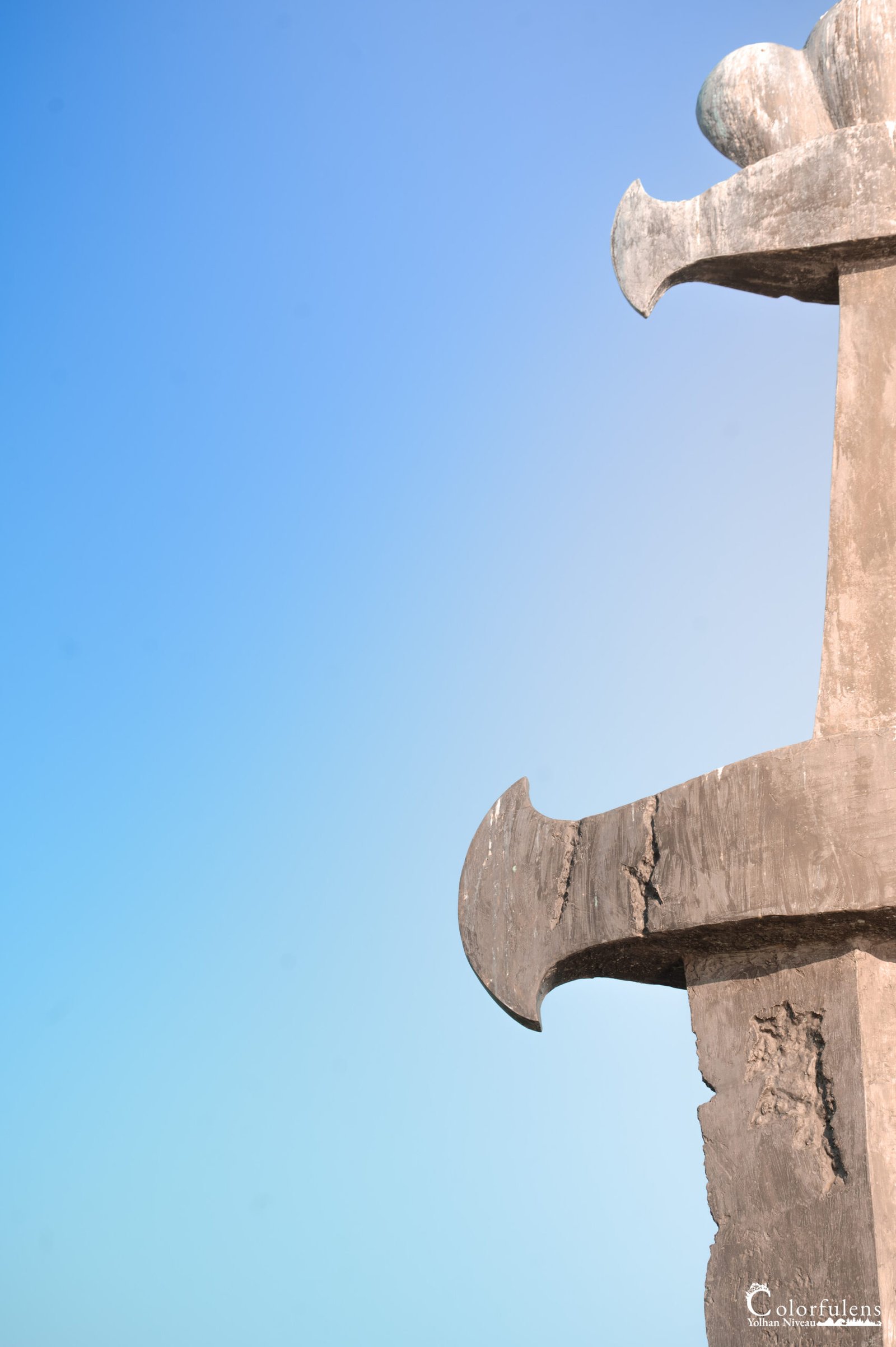 Photographie d'une sculpture moderne se détachant contre un ciel bleu clair, symbolisant l'harmonie entre l'art et la nature.