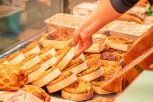 Une main sélectionne un des gâteaux traditionnels, mettant en lumière la qualité et l'artisanat des douceurs de la biscuiterie Vénètes, un appel à la gourmandise.