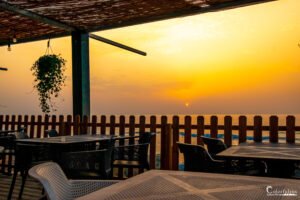 Une terrasse déserte face à l'océan au coucher du soleil, avec des teintes crépusculaires et une ambiance de tranquillité invitant à la détente.