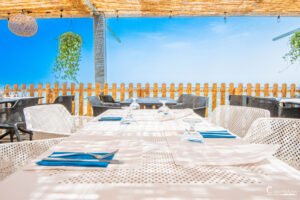 Terrasse extérieure du Camping Merendella offrant une vue imprenable sur la mer avec ciel bleu, idéale pour un déjeuner ensoleillé.