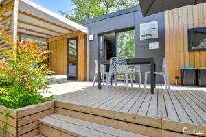 Mobil-home moderne avec terrasse en bois, table et chaises élégantes au camping Merendella