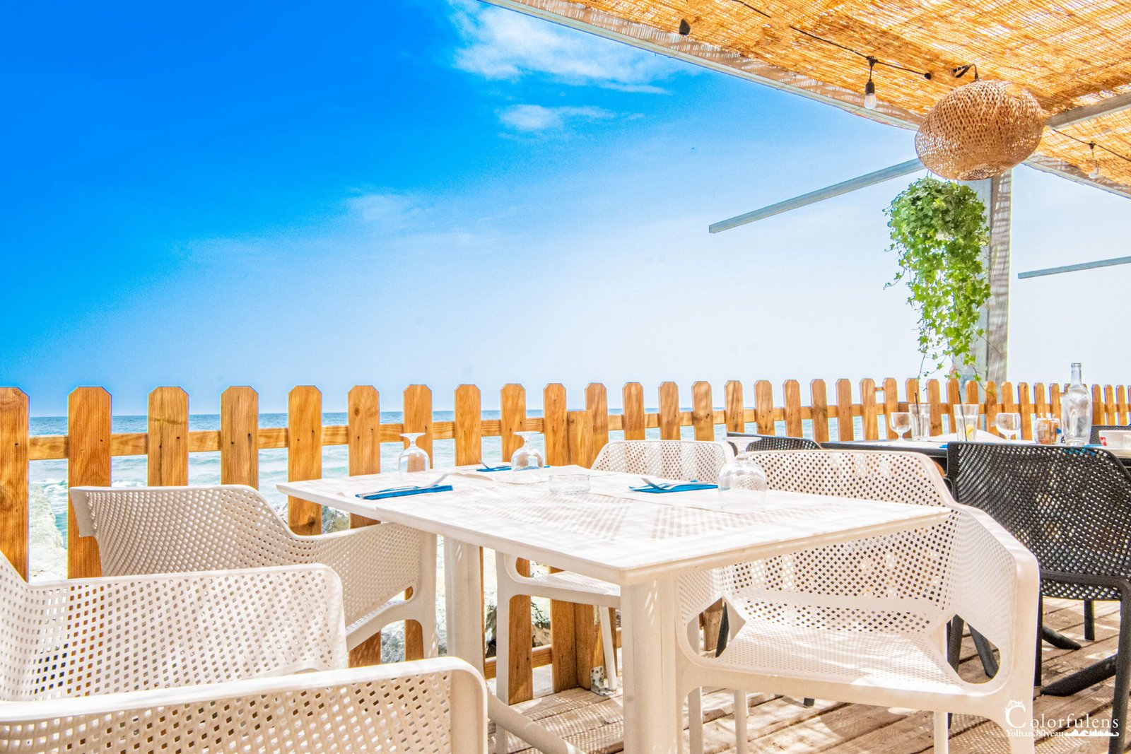 Terrasse de restaurant en Corse offrant une vue sur la mer Méditerranée sous le ciel d'un été calme, créant un cadre parfait pour la détente.