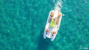 Journée ensoleillée entre amis sur un bateau à fond de verre en mer turquoise, reflétant bonheur et détente sous un ciel dégagé.