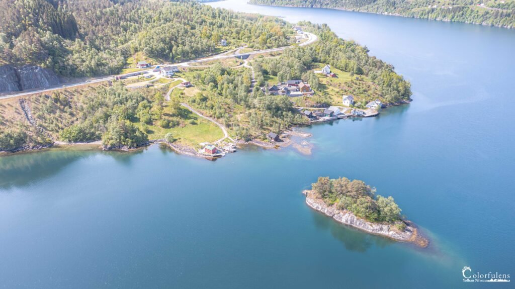 Vue aérienne du camping Gaupholm en Norvège montrant une communauté entourée par la nature avec un lac, des forêts et des montagnes.