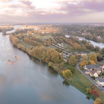 Vue aérienne d'Amboise en automne, montrant la majesté de la Loire entourée de couleurs chaudes et dorées.