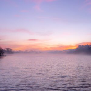 Lever de soleil magique sur l'étang de Noyalo, où la brume matinale danse au-dessus des eaux paisibles, créant une ambiance surréaliste et poétique.
