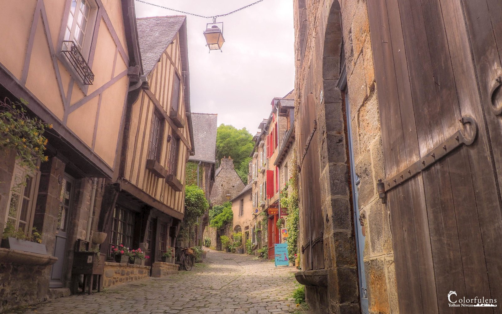 Une charmante scène médiévale à Dinan, révélant des maisons en colombage colorées et des pavés anciens qui reflètent l'héritage breton.