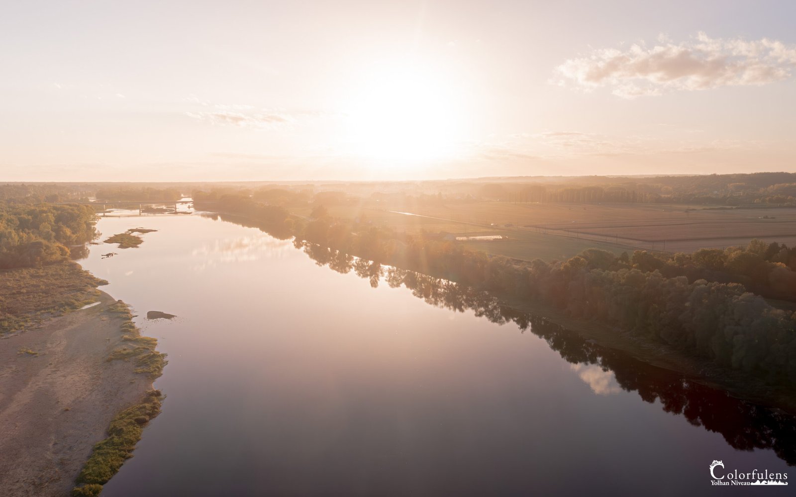 Coucher de soleil sur la Loire dévoilant des reflets dorés sur l'eau, créant une scène paisible et harmonieuse.